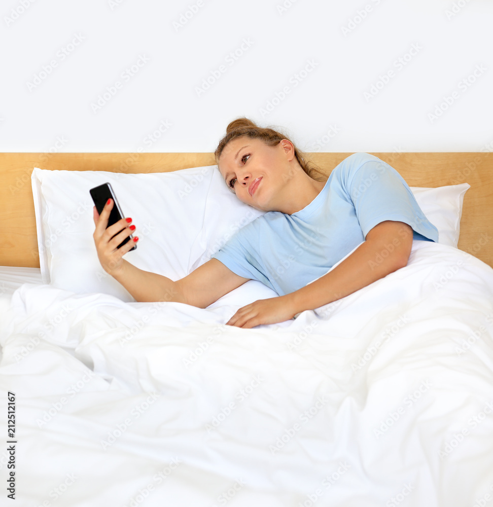 Woman relaxing on her bed,using smarthone Woman relaxing on her bed,using smarthone