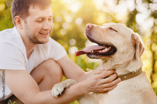Owner young man with labrador dog outdoors green grass. Concept friendship