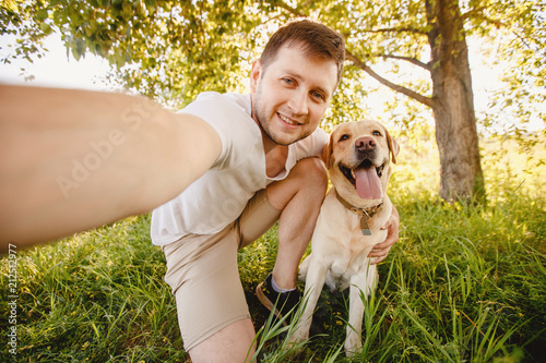 Man is smile fun with their dog labrador retriever outdoors. Making selfie. Concept friendship