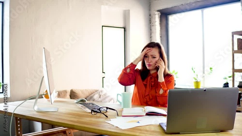 Upset businesswoman having phone conversation. Sad and stressed female office worker getting worried while talking on her mobile phone in modern office.