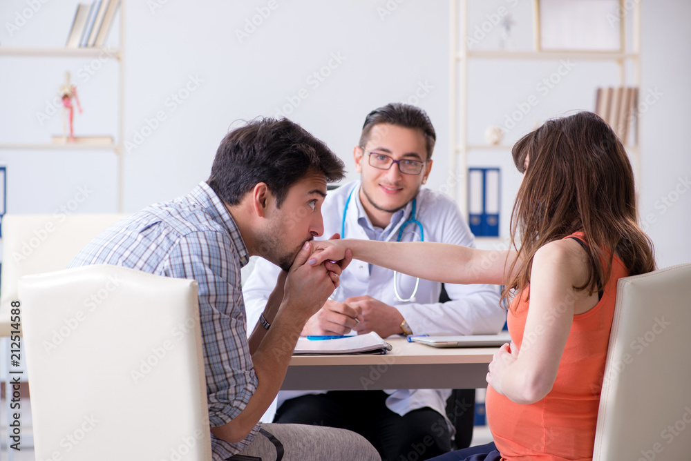 Pregnant woman with her husband visiting the doctor in clinic Pregnant woman with her husband visiting the doctor in clinic