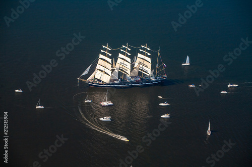A large sailboat, bark goes into the sea surrounded by many yachts.
The last windjammer bark Kruzenstern. photo