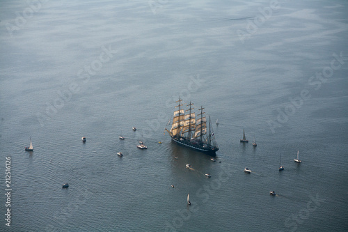 A large sailboat, bark goes into the sea surrounded by many yachts.
The last windjammer bark Kruzenstern. photo