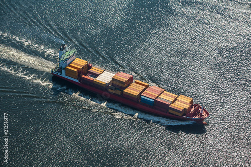 A sea vessel is a container ship at full speed in the open sea. View from above.  © Aleks Kend