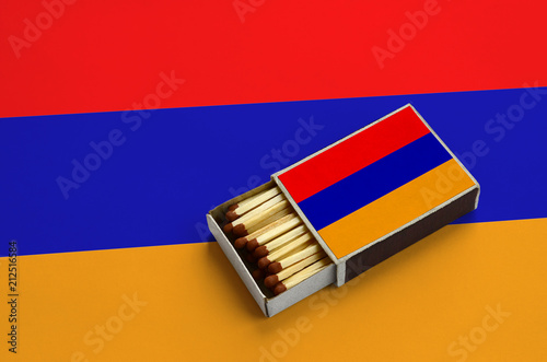 Armenia flag  is shown in an open matchbox, which is filled with matches and lies on a large flag photo