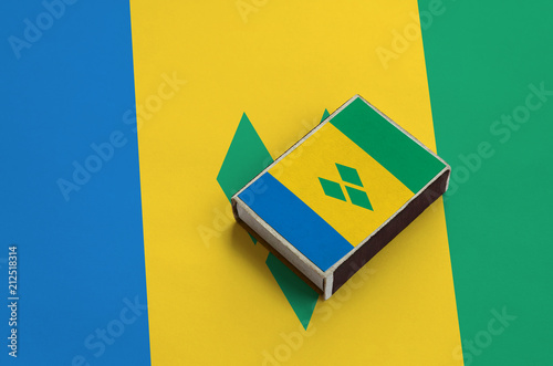 Saint Vincent and the Grenadines flag  is pictured on a matchbox that lies on a large flag photo