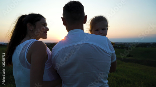 Pregnant couple with toddler daughter have leisure time outdoors at sunset. Happy young parents with child at sunset. Father holding kid. Parenthood, pregnancy, childhood, healthy, activity concept © yk_stock