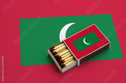 Maldives flag  is shown in an open matchbox, which is filled with matches and lies on a large flag photo