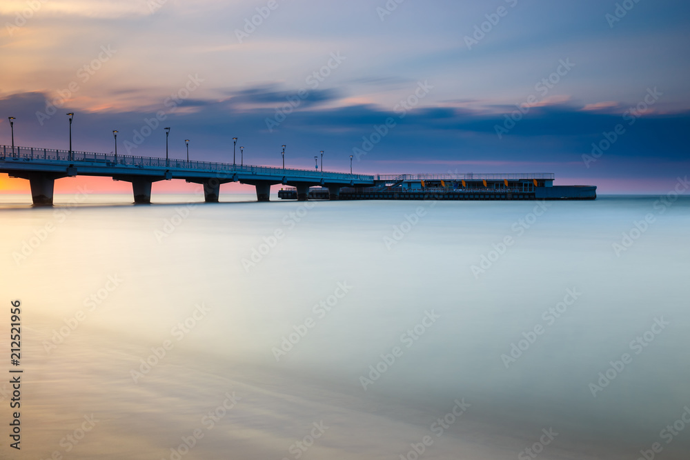 quiet beach with pier at sunset, long time exposure