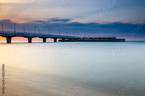 quiet beach with pier at sunset, long time exposure © dziewul