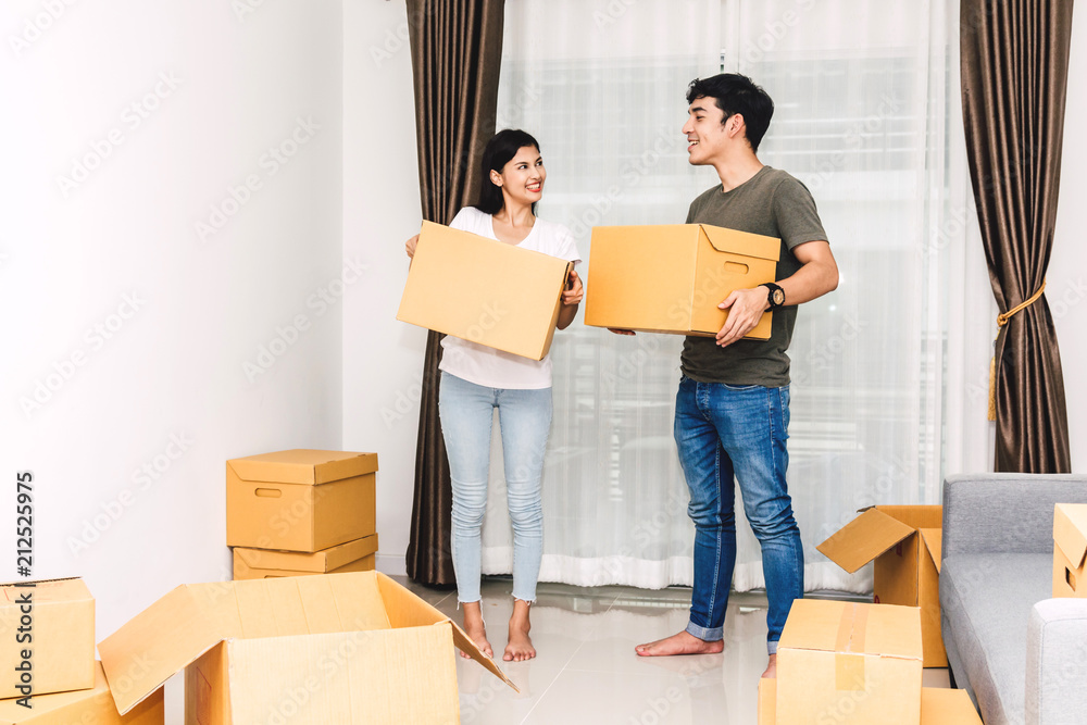Happy young couple holding box and moving into their new home.House moving and real estate concept Happy young couple holding box and moving into their new home.House moving and real estate concept