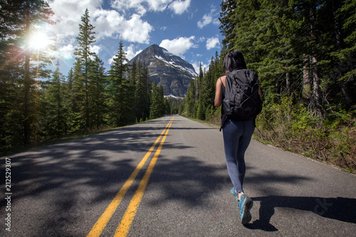 Solo female adventurer and nomadic wanderlust world traveller walking on long journey  backpacking on empty road 