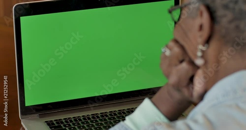 Senior black woman looking at a green screen chroma key computer screen