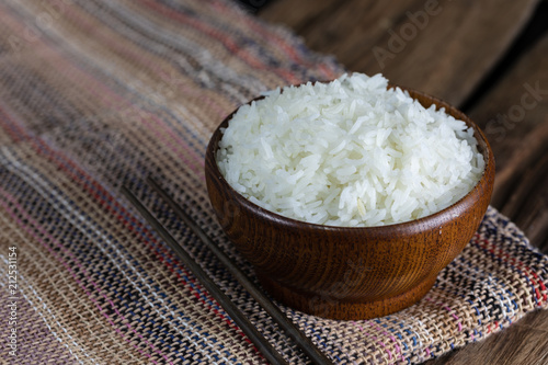 cooked rice in wooden bowl with smoke on wooden floor