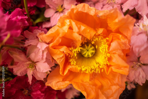 orange flower with yellow center in pink bouquet