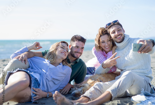 Group of friends having fun on beach during autumn day