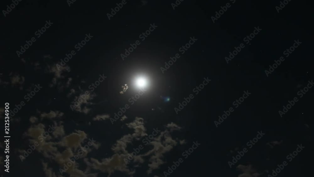 Time lapse of clouds moving across the sky under moon at night time with some stars visible in the background Time lapse of clouds moving across the sky under moon at night time with some stars visible in the background