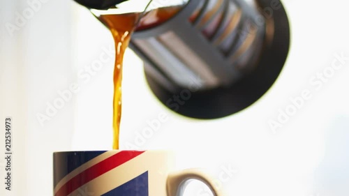 pouring coffee from a French press into a mug with the British flag on it with speed ramp an slow-motion photo