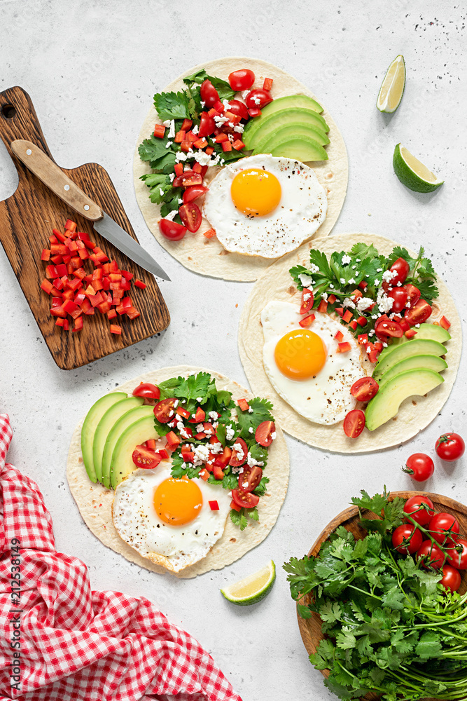 Tortilla with avocado, salsa and egg on concrete background. Top view