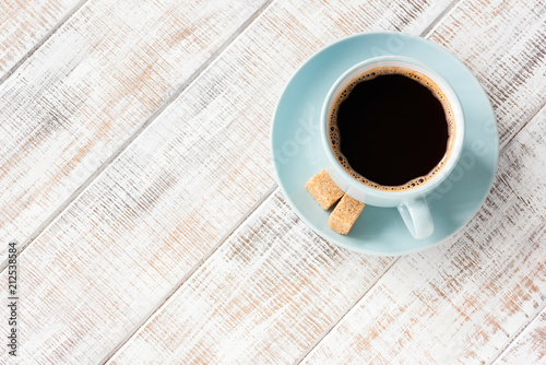 Blue cup of black coffee on white wooden table with copy space for text. Table top view