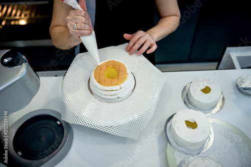 Asian women is confectionery bag squeezing tea cream on cupcakes, a rounded cakes for welcoming people to the evening party.