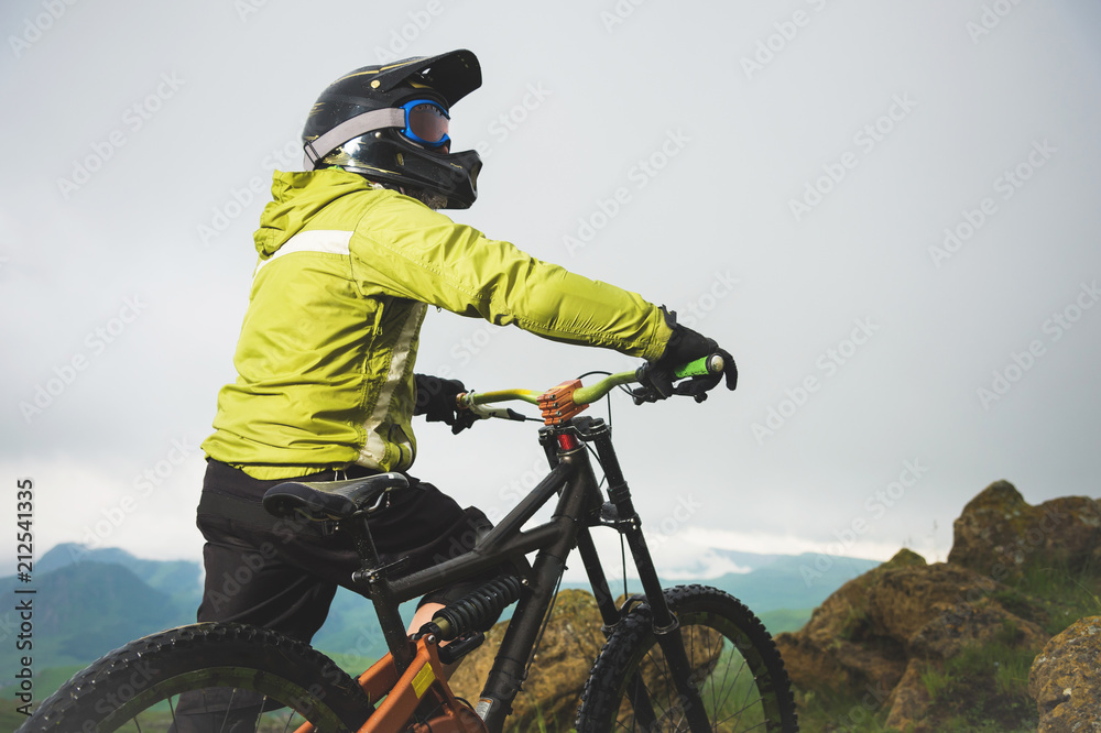 Naklejka premium Portrait of a man aged on a mountain bike in the mountains in cloudy weather. Mountain bike concept