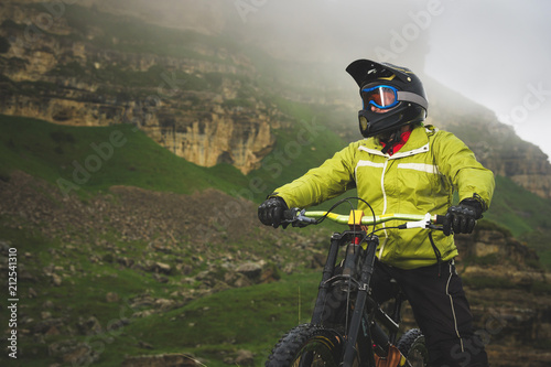 Portrait of a man aged on a mountain bike in the mountains in cloudy weather. Mountain bike concept