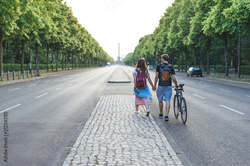 Canvas Print rear view of couple of tourists with bicycle walking at street in Berlin, German