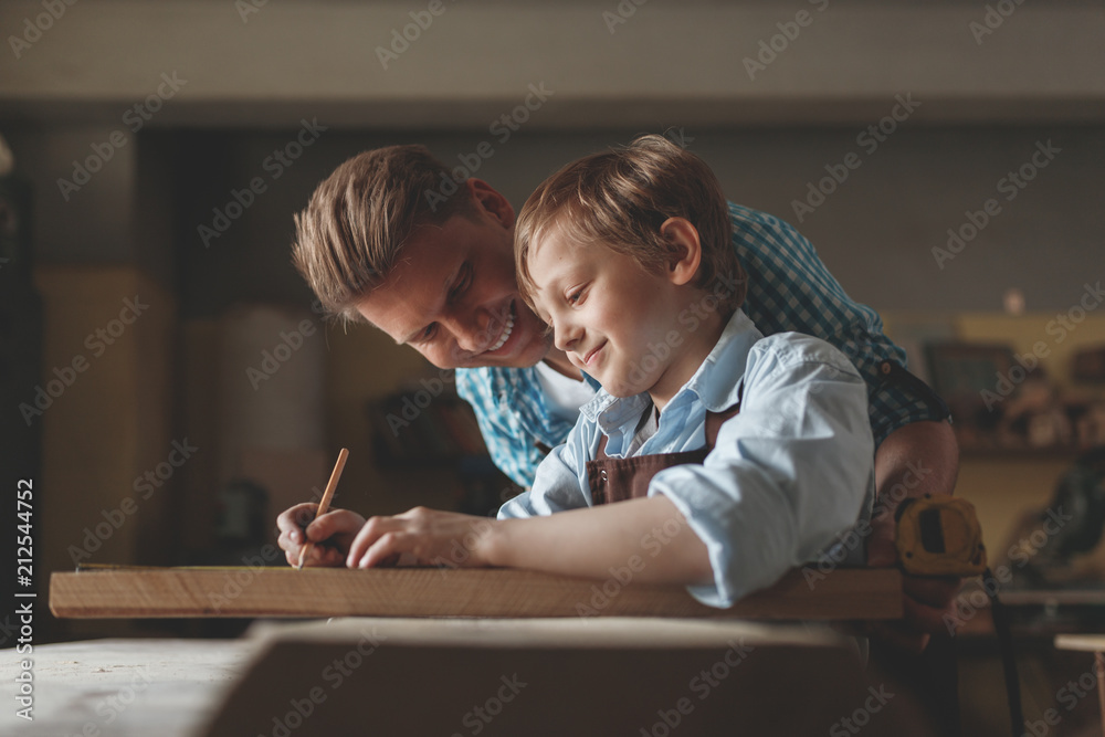 Smiling father and a little son in carpentry Smiling father and a little son in carpentry
