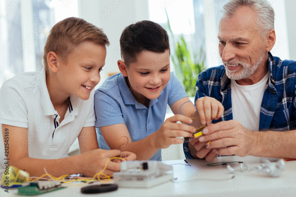 Young genius. Nice positive boys building a robot while enjoying engineering Young genius. Nice positive boys building a robot while enjoying engineering