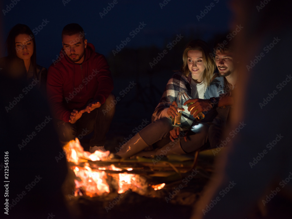 Obraz premium Couple enjoying with friends at night on the beach