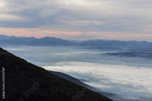 Beautiful aerial view of Umbria valley in a winter morning  with fog covering trees and house and warm colors in the sky