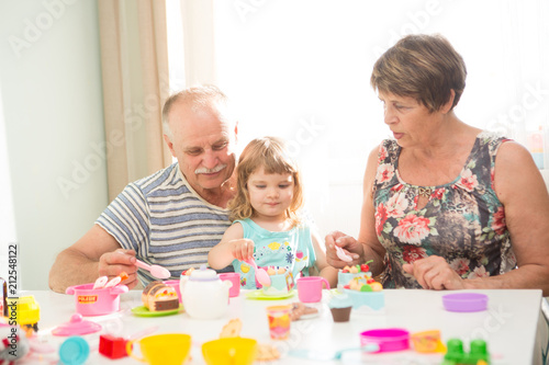 Grandparents and granddaughter are playing with toys and spending time together at home.