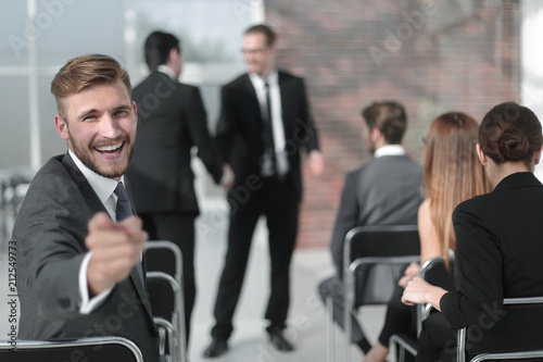 businessman sitting in the conference room, pointing at you