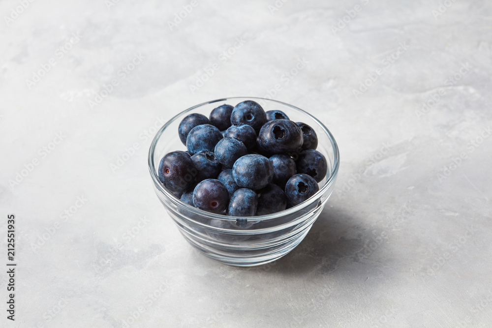 Blueberries in is a small glass bowl on gray stone background Blueberries in is a small glass bowl on gray stone background