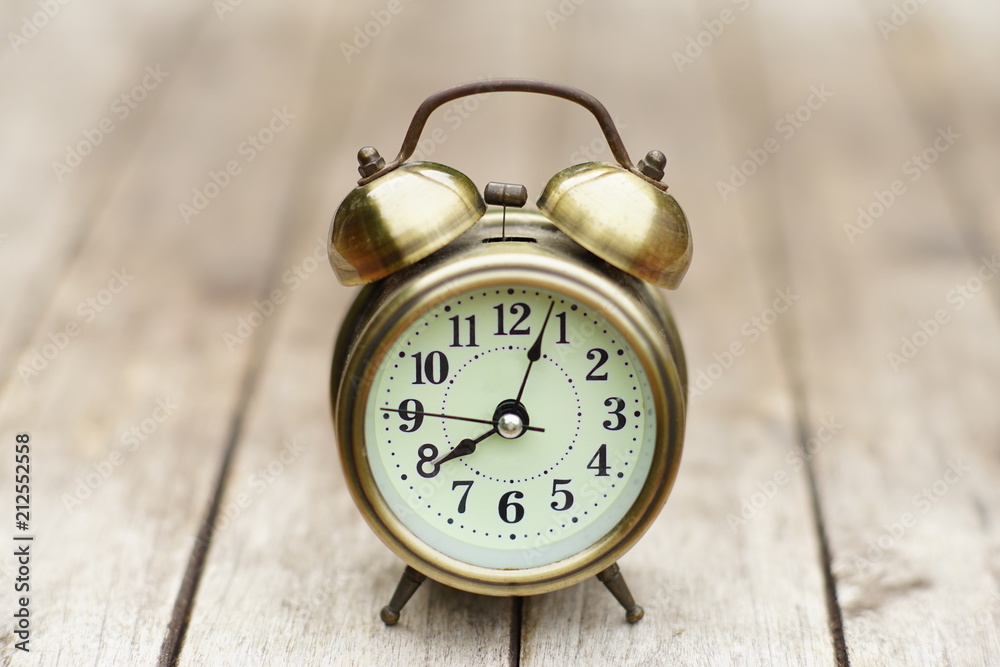 Analog alarm clock on wooden table with blur green garden background, 8 am., copy space Analog alarm clock on wooden table with blur green garden background, 8 am., copy space