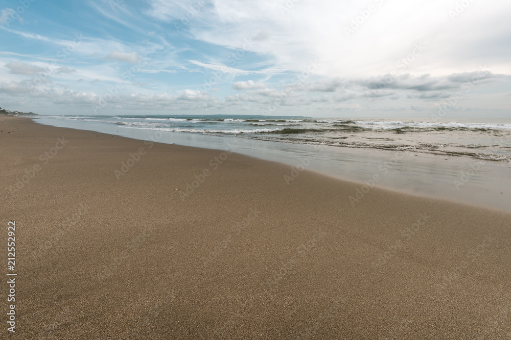 sea wave reach sandy beach under cloudy sky