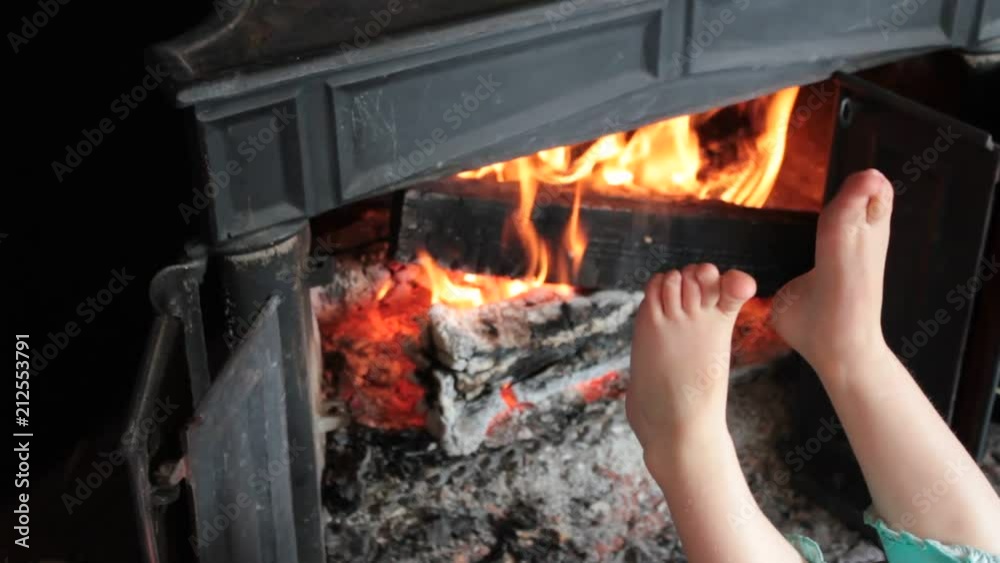 A little child's feet getting warm by the fire. Then she rubs them together. A little child's feet getting warm by the fire. Then she rubs them together.