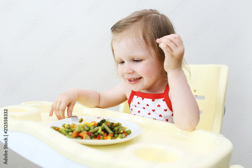 Portrait of happy little 2 years girl eating fish with vegetables Portrait of happy little 2 years girl eating fish with vegetables