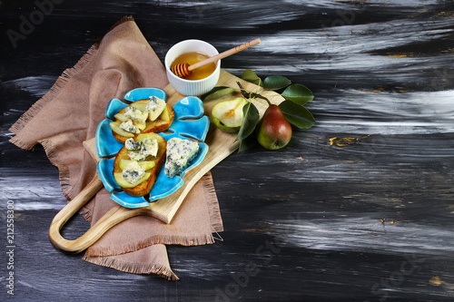 Fresh sweet Pears salad and bruschetta with blue cheese, walnut on wooden board background. Close up, selective focus. photo