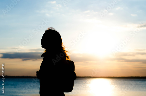 Woman silhouette standing alone in sunset scene,beautiful sky in the evening. © patcharee11