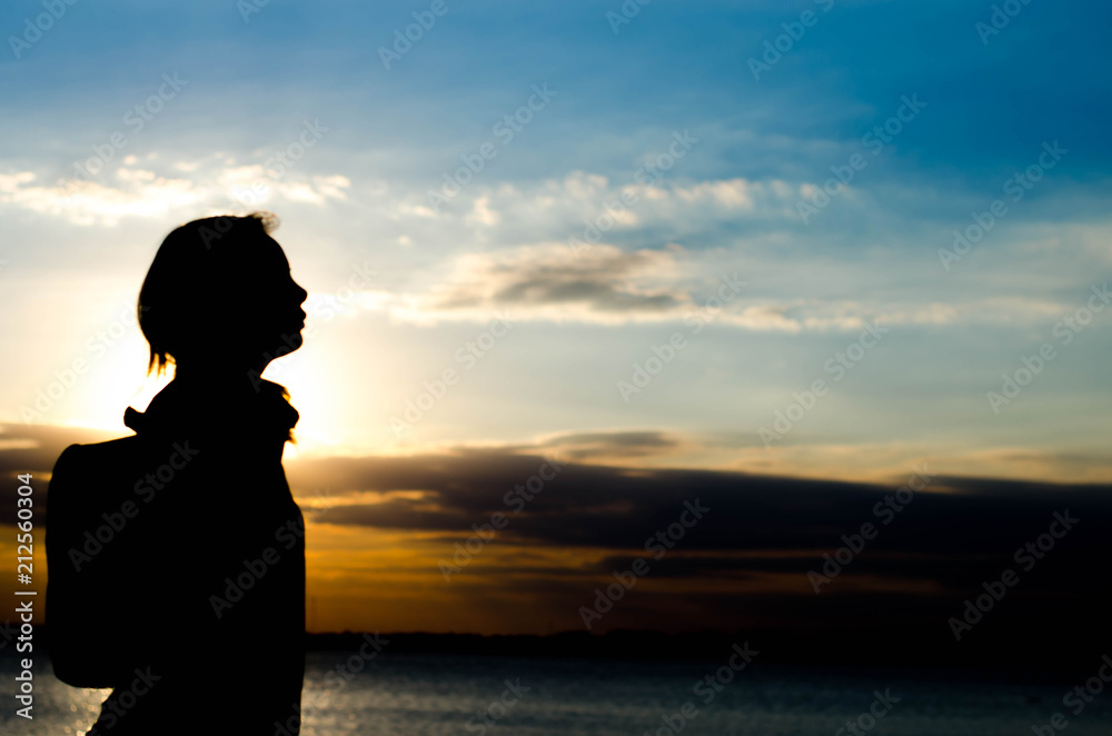 Woman silhouette standing alone in sunset scene,beautiful sky in the evening.