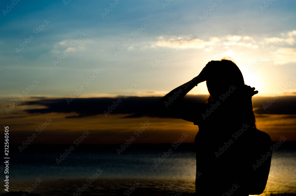 Woman silhouette standing alone in sunset scene,beautiful sky in the evening.