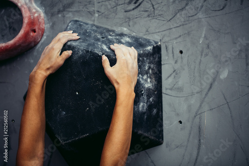 Female climber hands clenching artificial boulder in climbing gym, closeup shot
