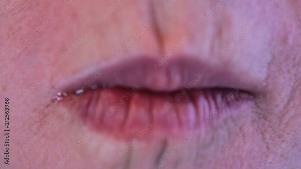 An adult woman places a nacho chip in her mouth and chews it up. Very close up of just her lips and mouth. An adult woman places a nacho chip in her mouth and chews it up. Very close up of just her lips and mouth.