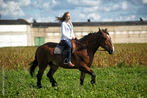 blonde riding a horse in a field