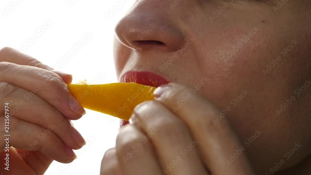 beautiful woman licks and eating piece of orange on a white background. Great food for a healthy lifestyle. slow motion