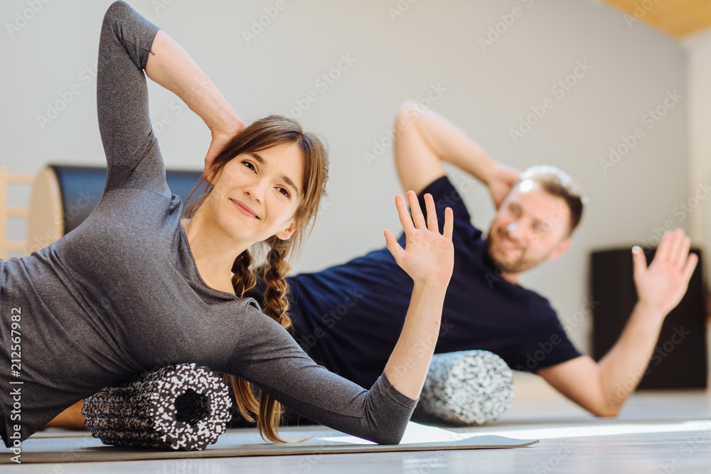 woman instructor performing back exercise on a foam roller at