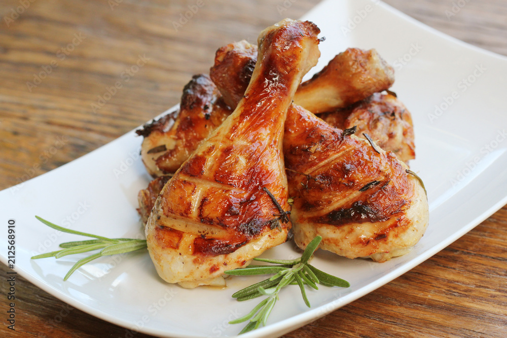 Grilled chicken legs with rosemary served on white plate. Dinner background Grilled chicken legs with rosemary served on white plate. Dinner background