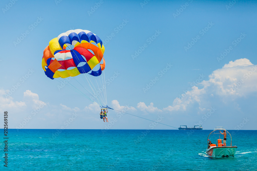 Couple of tourists flying on a colorful parachute